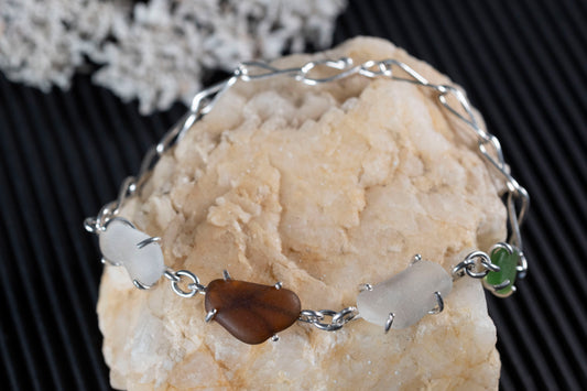 Linked prong settings holding sea glass in the Dark Artifices inspired bracelet.