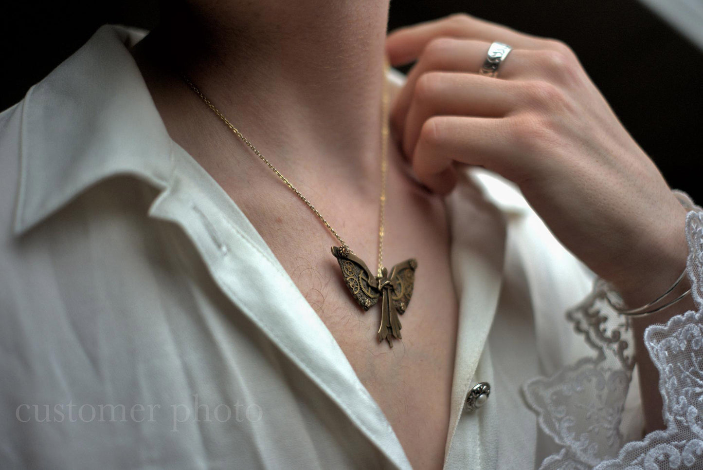 Tessa's Clockwork Angel necklace worn by a person with a white shirt and lace detail.