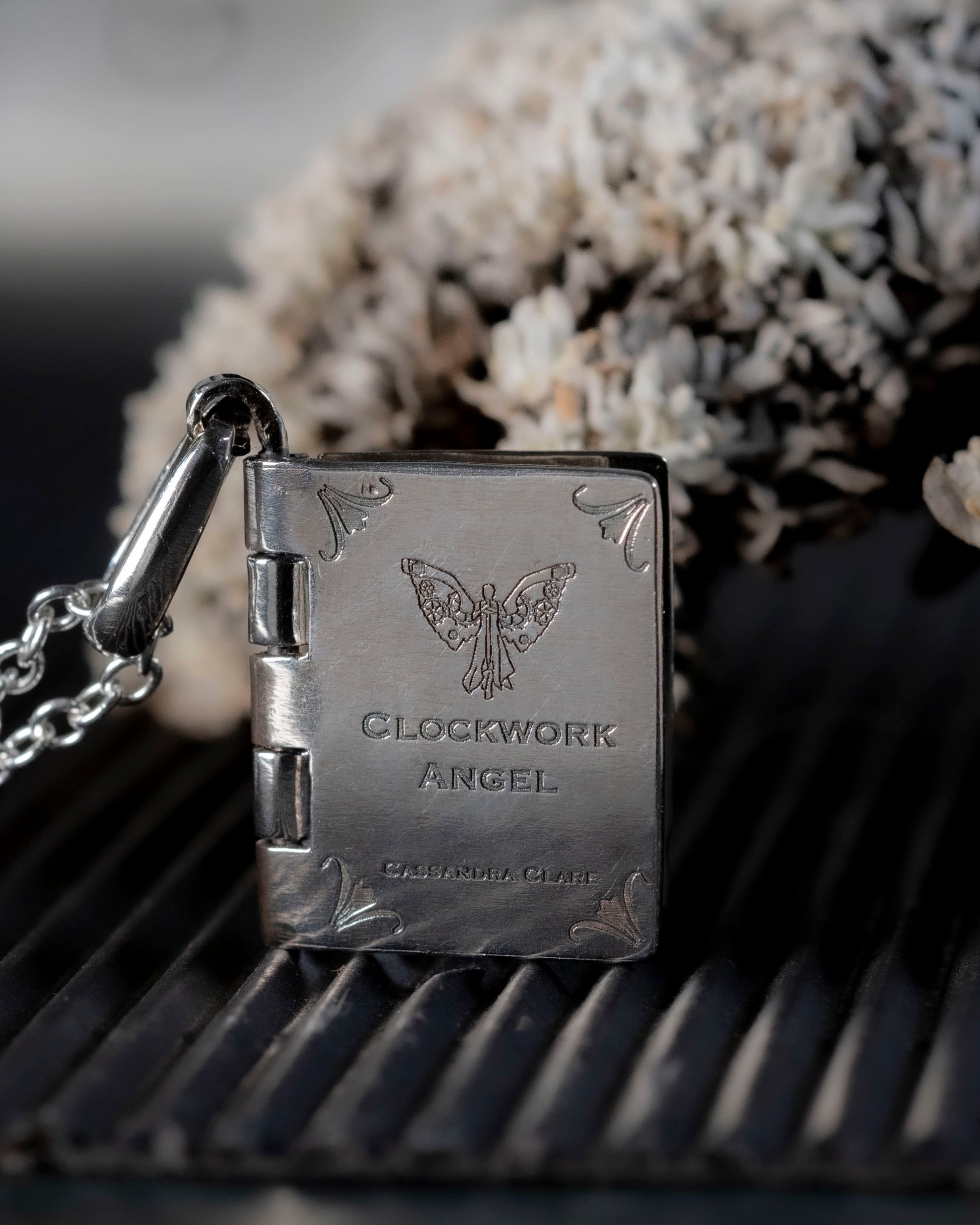 Close-up of the laser-engraved clockwork angel on the book pendant cover.