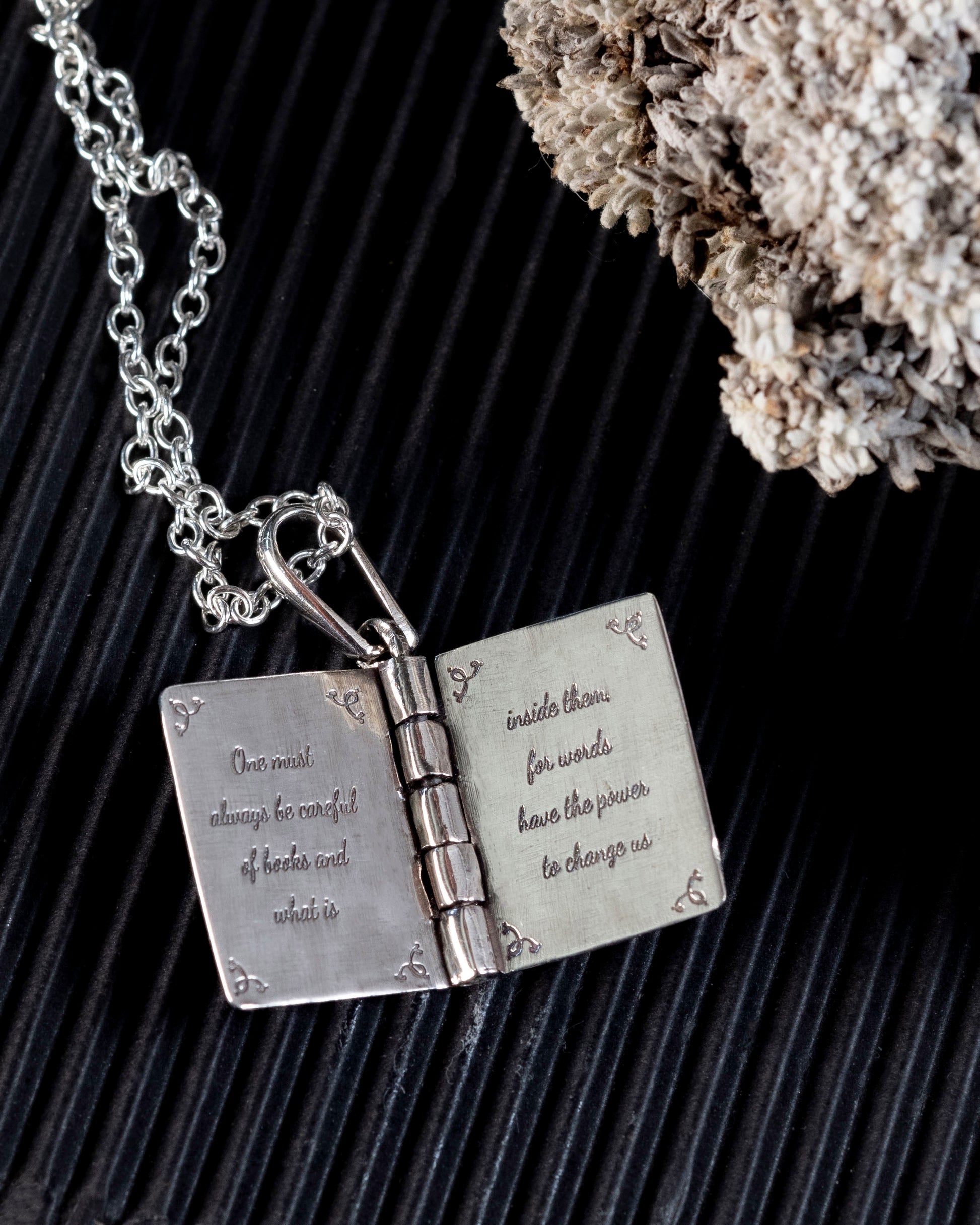 The hinged book pendant open, showing the engraved quote inside
