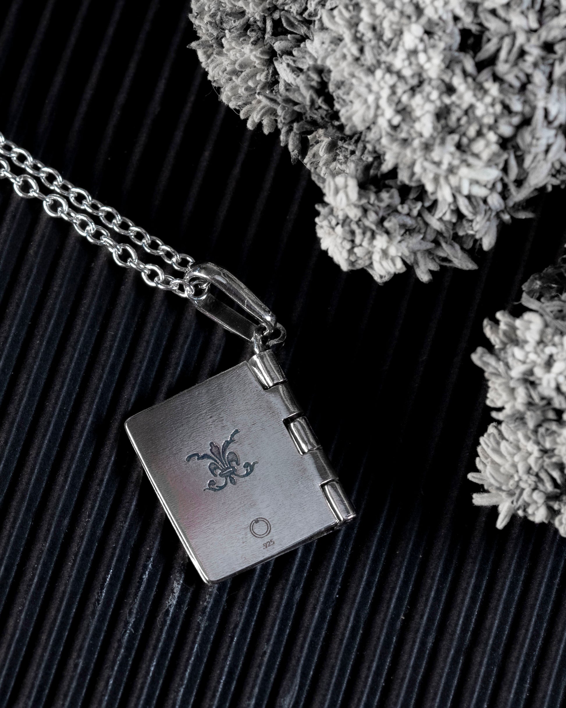The back of the silver book pendant with a flourish engraving.