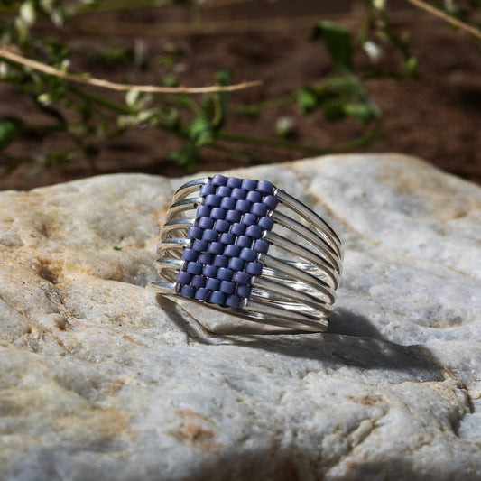 Silver wire ring with lavender beaded band on a rock