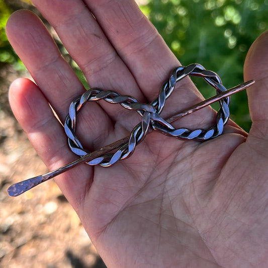 The copper infinity hair accessory, showing its polished finish
