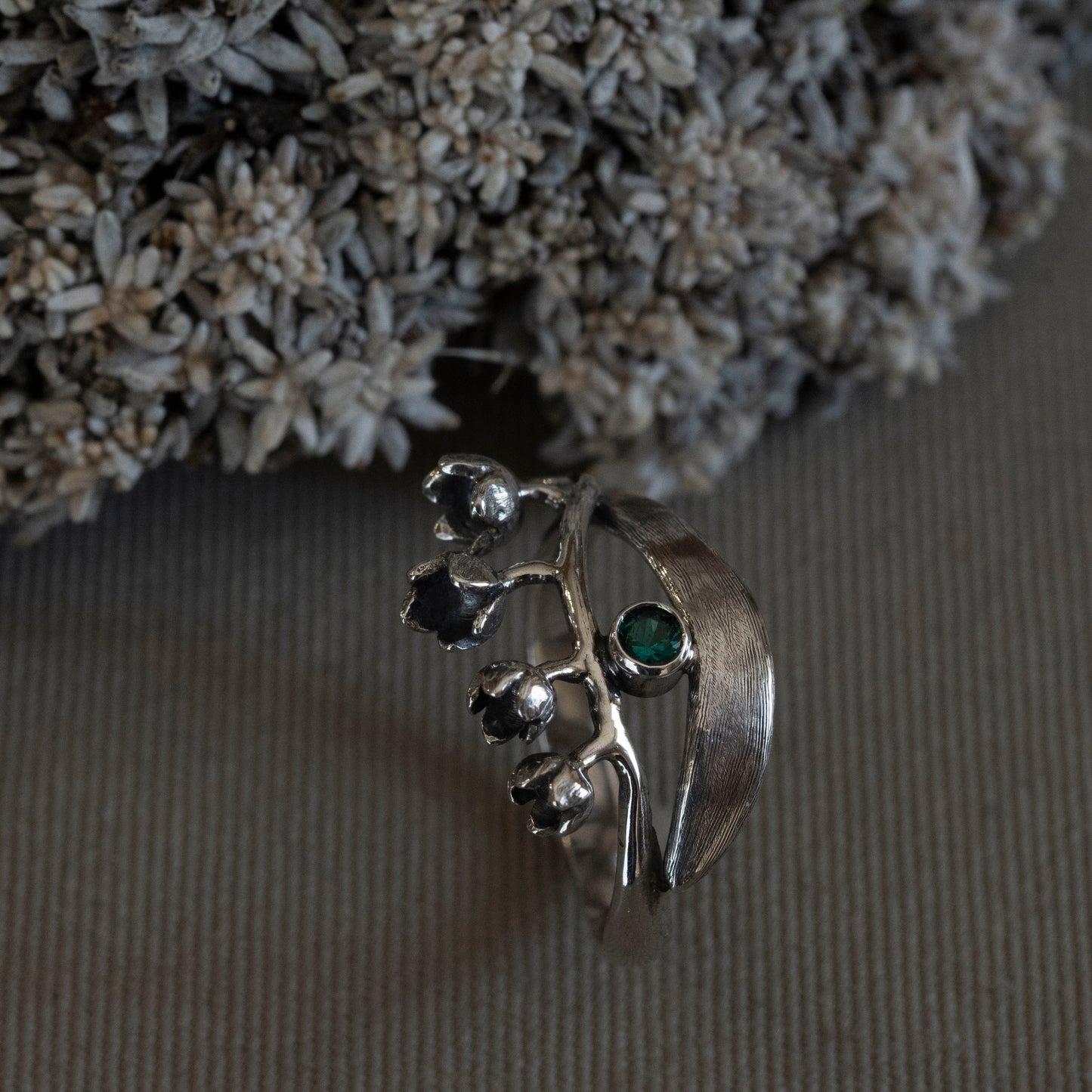 May Lily of the Valley wrap ring in sterling silver with a 3mm lab-created emerald, hand-fabricated botanical jewelry by Hebel Design.