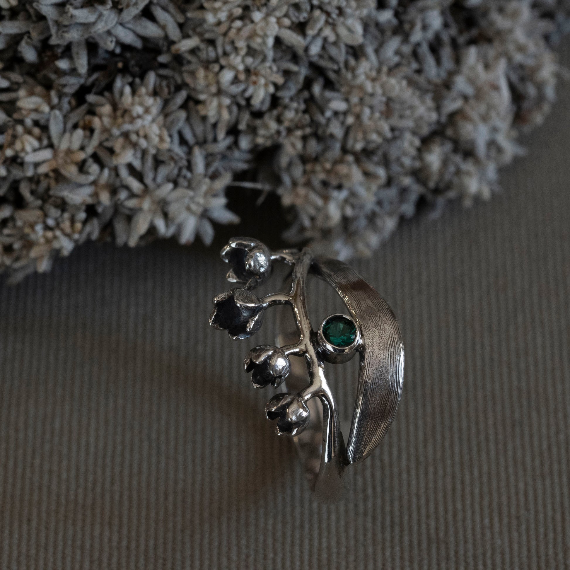 May Lily of the Valley wrap ring in sterling silver with a 3mm lab-created emerald, hand-fabricated botanical jewelry by Hebel Design.
