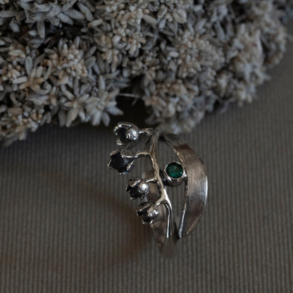May Lily of the Valley wrap ring in sterling silver with a 3mm lab-created emerald, hand-fabricated botanical jewelry by Hebel Design.