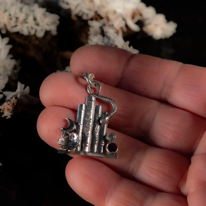 Close-up of the silver bookshelf pendant showing the bookend detail and the snake winding through