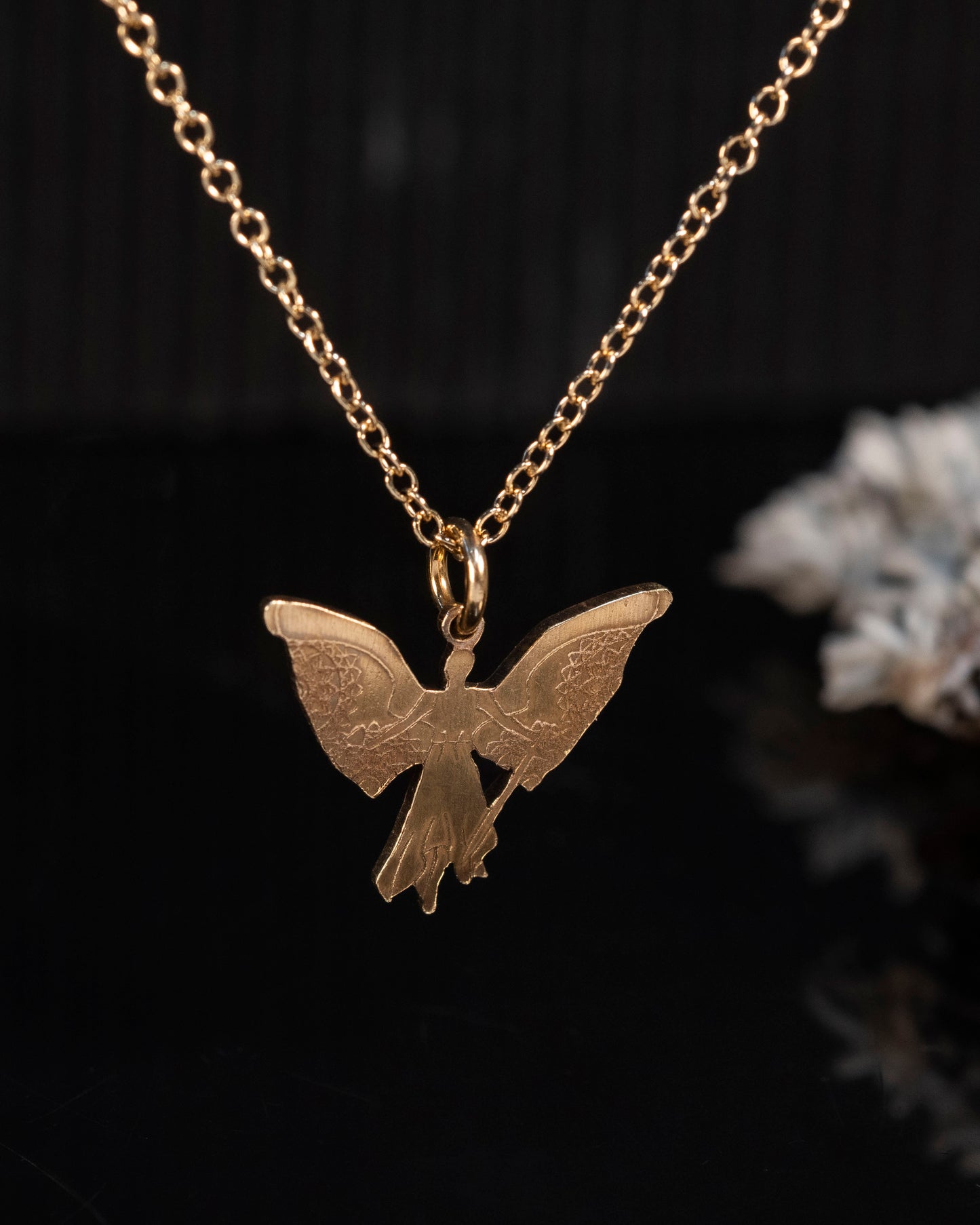 Close-up of the brass Angel Raziel pendant with intricate details of the angel, cup, and sword.