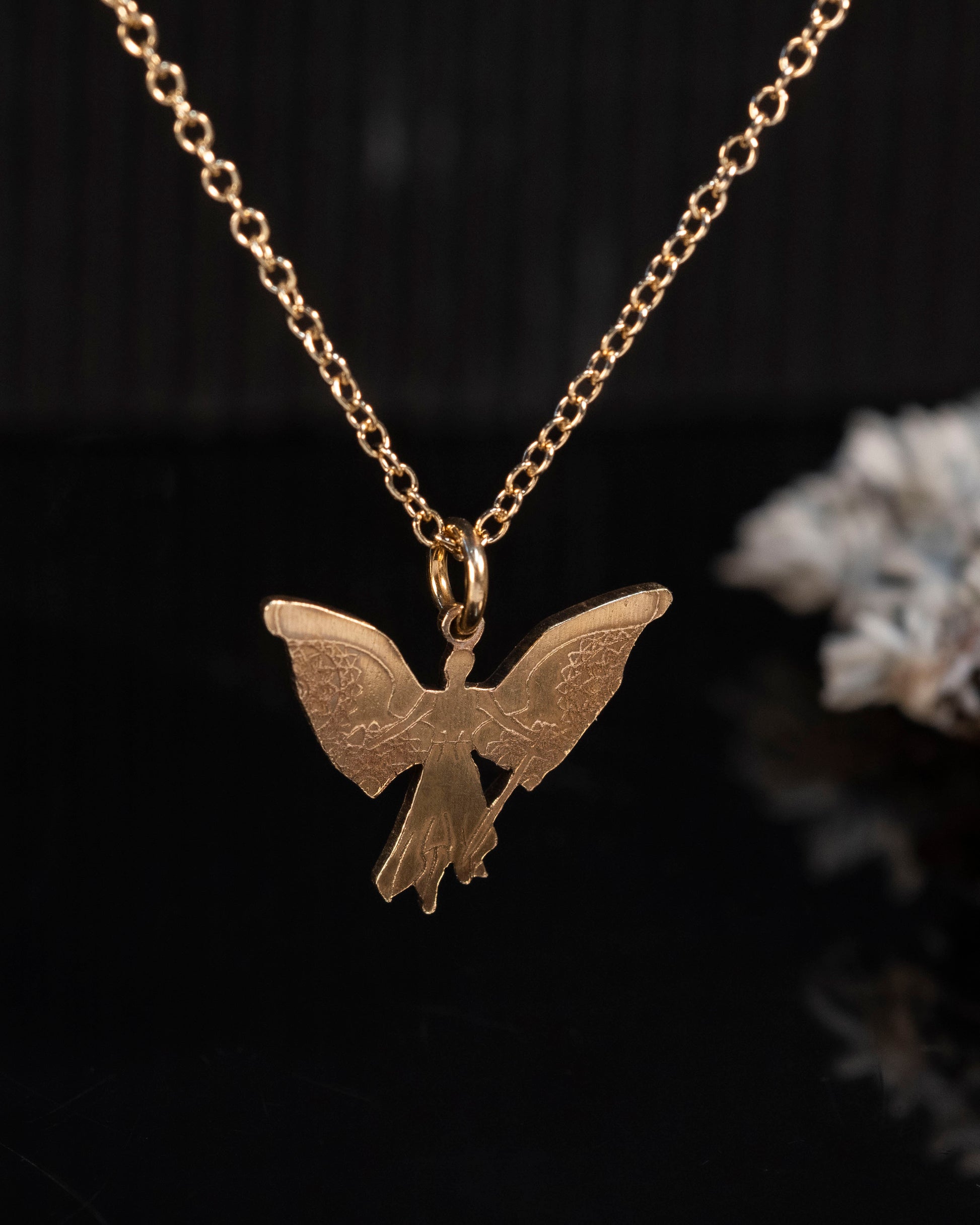 Close-up of the brass Angel Raziel pendant with intricate details of the angel, cup, and sword.