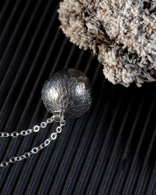 Close-up of the laser-engraved mandala texture on the silver acorn top.