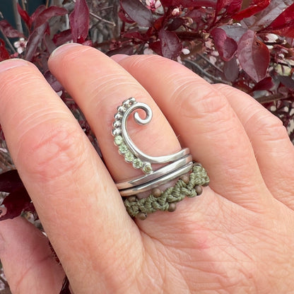 Close up of the unfurling fern ring paired with macrame ring